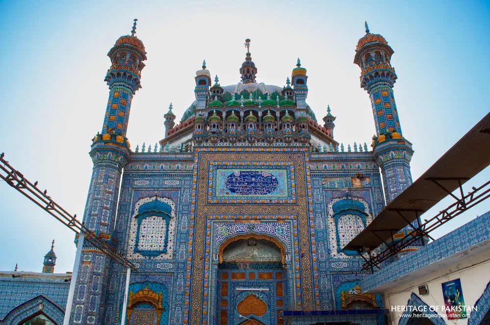 Tiled shrine front with green domes seen from the courtyard