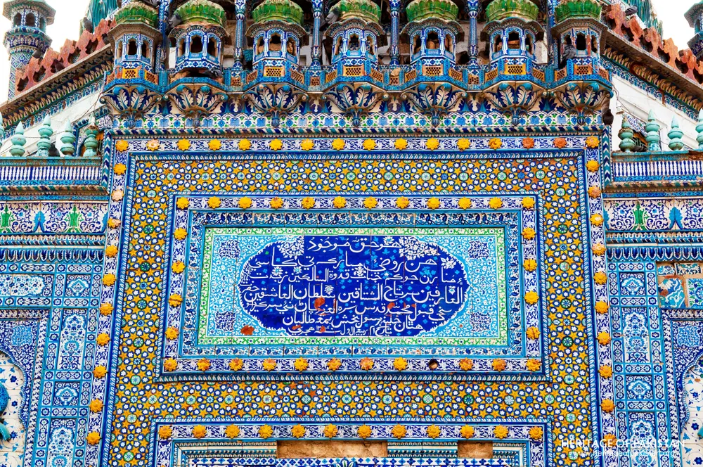 Tiled facade panel with calligraphy below green-domed turrets