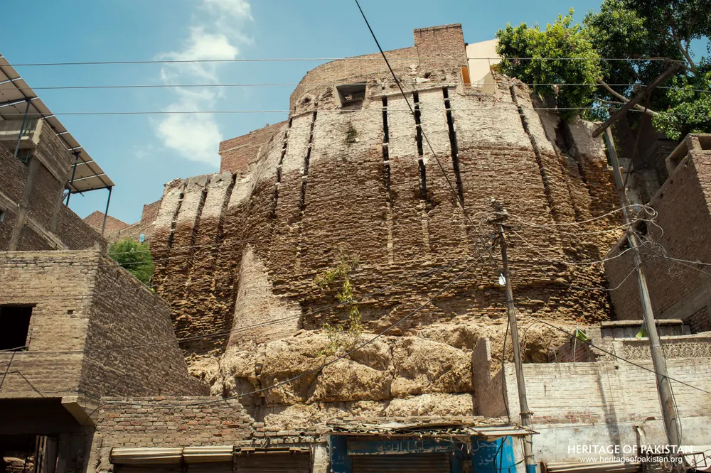 Massive stepped bastion of Pakka Qila with modern brick houses built atop its crown