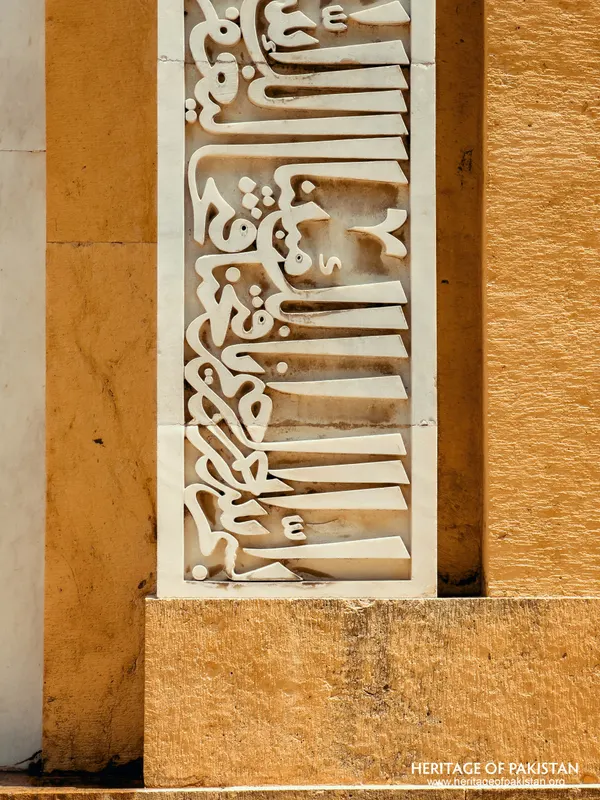 White marble calligraphy panel at the base of a yellow stone wall