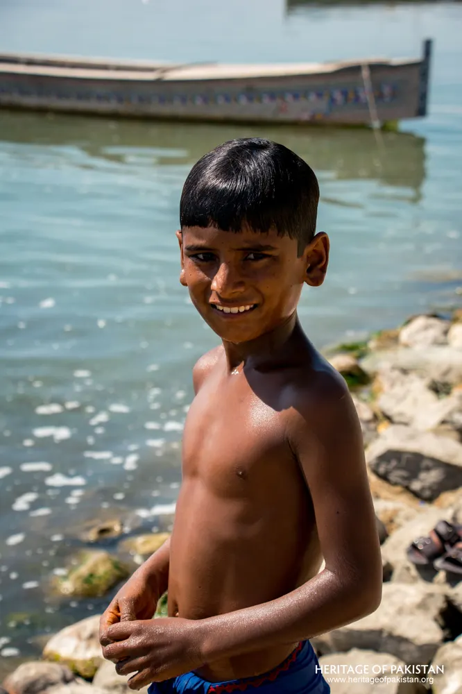 Smiling boy standing on a rocky lake shore