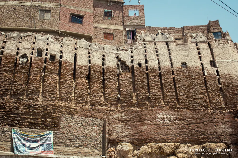 Pakka Qila's rampart with modern brick houses built into its upper courses, a cloth banner hanging below