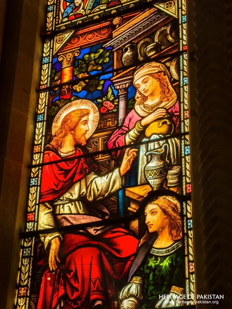 Stained-glass panel of Christ with two women beside a vessel-laden shelf at Holy Trinity Church