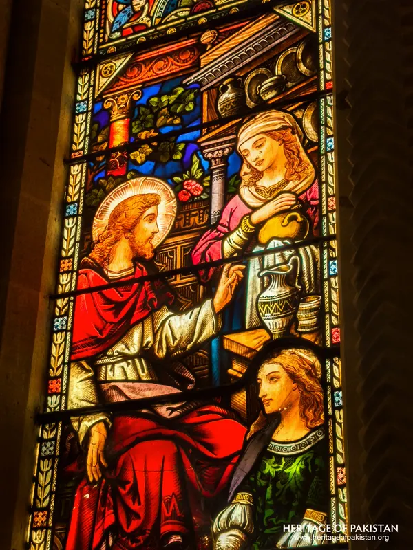 Stained-glass panel of Christ with two women beside a vessel-laden shelf at Holy Trinity Church