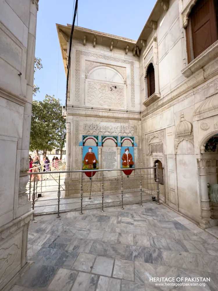 Carved marble wall with painted relief portraits of two saints in an alcove at Sadhu Belo Temple