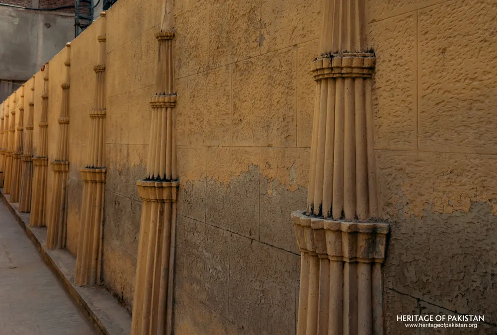 Close view of fluted column shafts repeating along a boundary wall