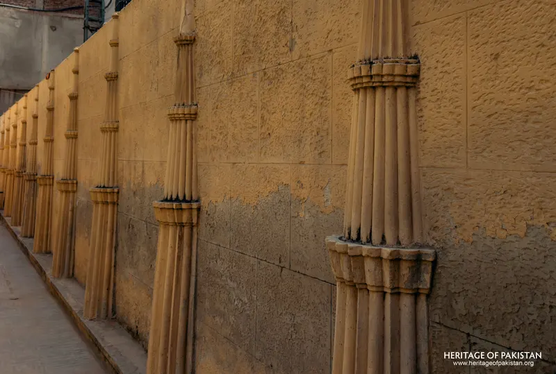 Close view of fluted column shafts repeating along a boundary wall