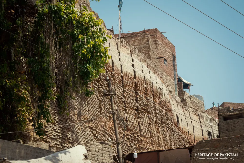 Eroded sloped section of Pakka Qila's rampart with a flag pole atop the wall