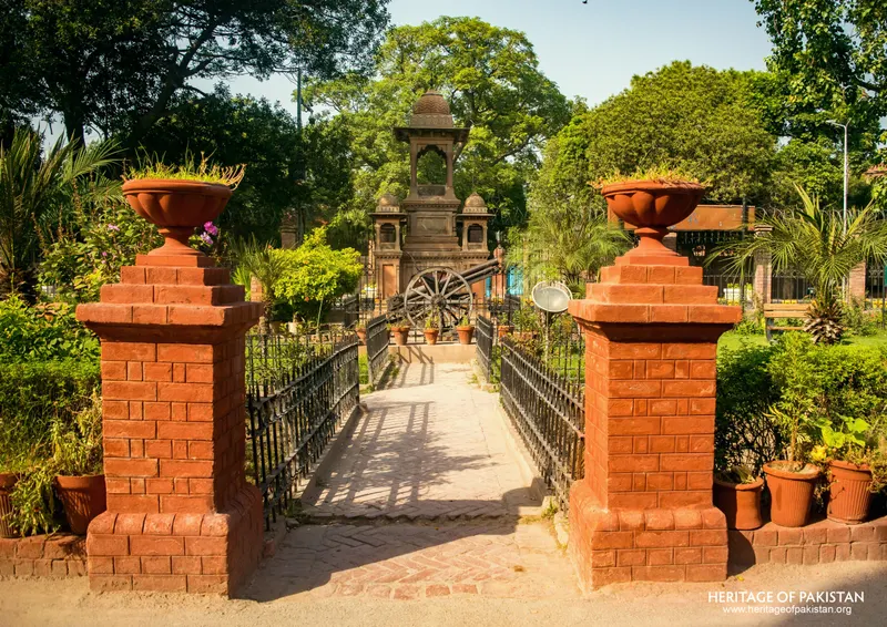 Red brick gate pillars with stone urns flanking an iron-railed path