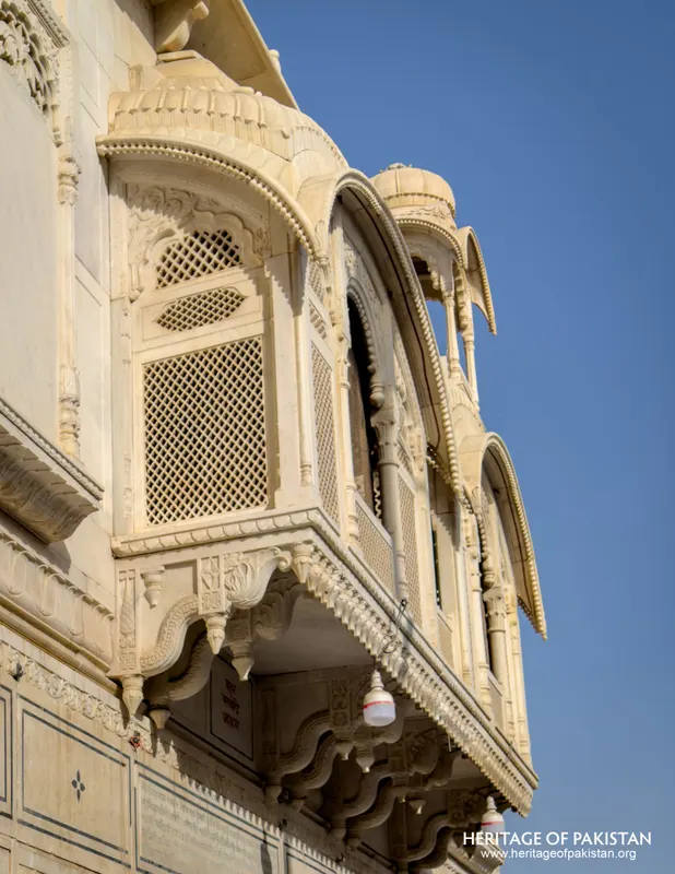 Man standing beneath the arched marble colonnade at the entrance of Sadhu Belo Temple
