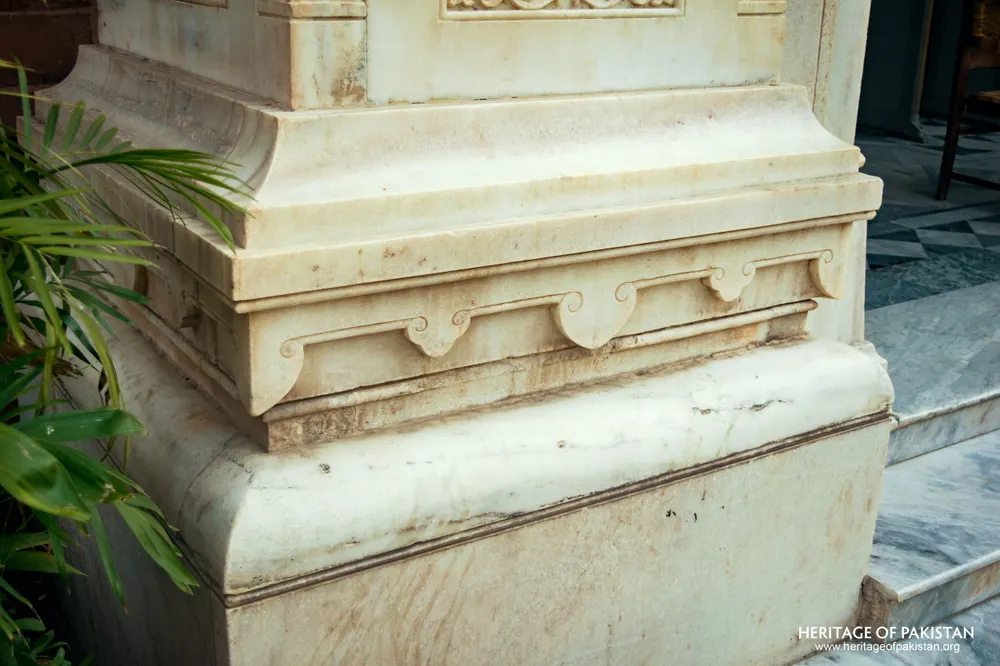 Close-up of a white marble column base with carved scroll detail