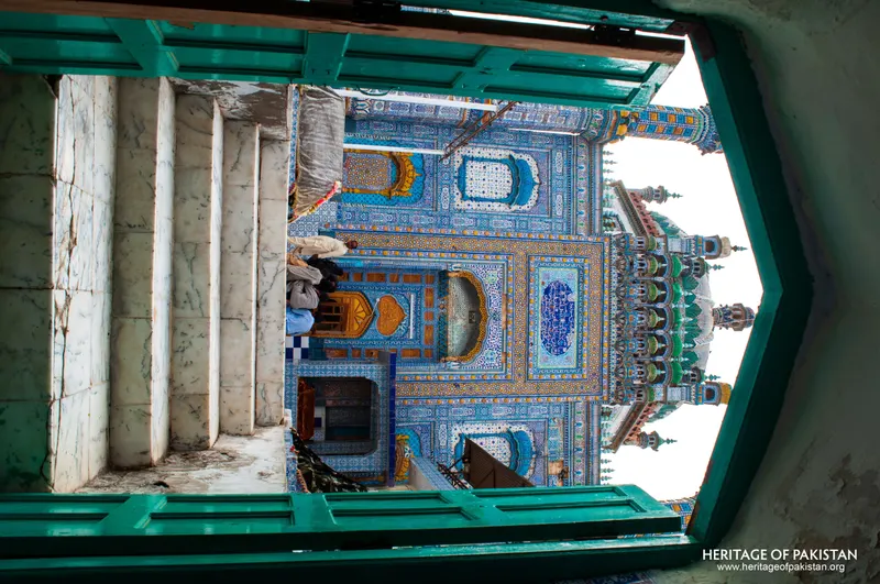 Tiled shrine seen through a green-framed window with a marble surround