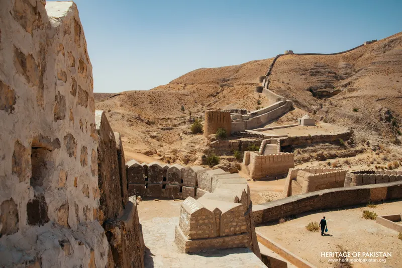 Fortified walls and crenellated parapets stepping across a dry hillside