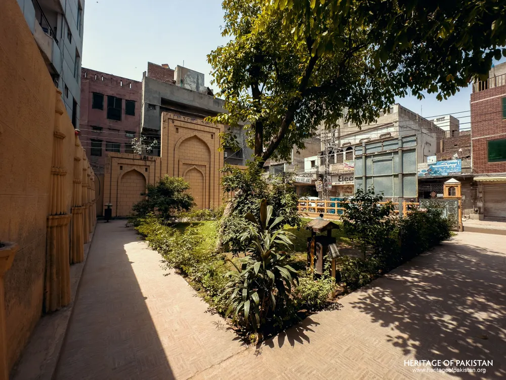 Paved pathway alongside a yellow sandstone wall with arched niches