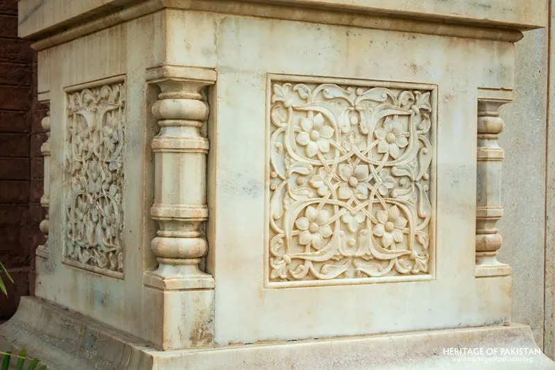 Close-up of a carved white marble plinth panel with floral motif