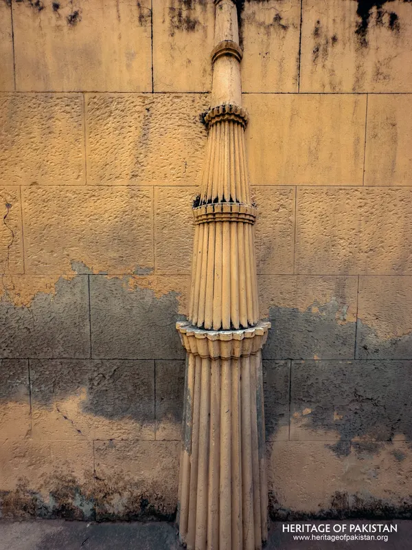 Full-length fluted column shaft against a pale stone wall