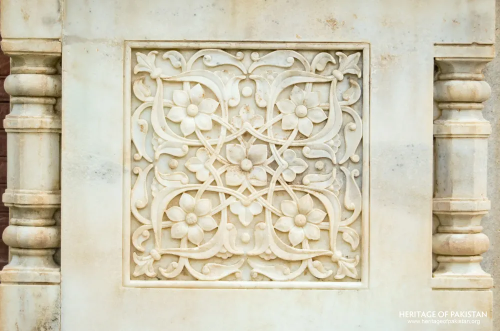 Close-up of a carved marble panel with flowering scroll design