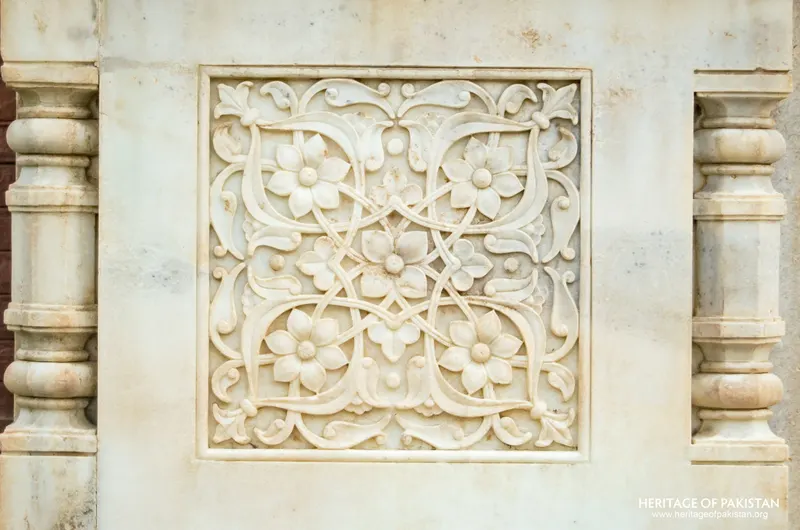 Close-up of a carved marble panel with flowering scroll design