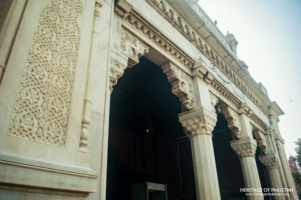 White marble portico with pointed arches and carved floral panel
