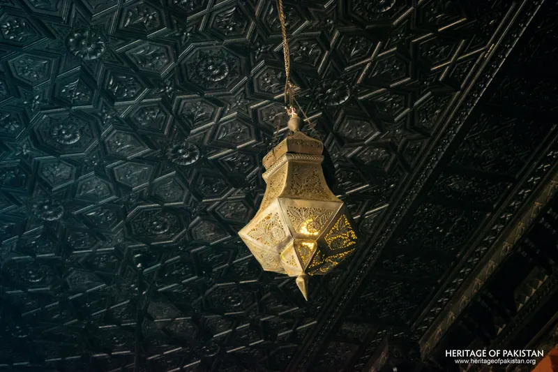 Brass star-shaped lantern hanging from a dark patterned ceiling