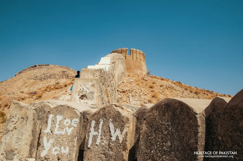 Crenellated parapet with graffiti, round bastion visible beyond