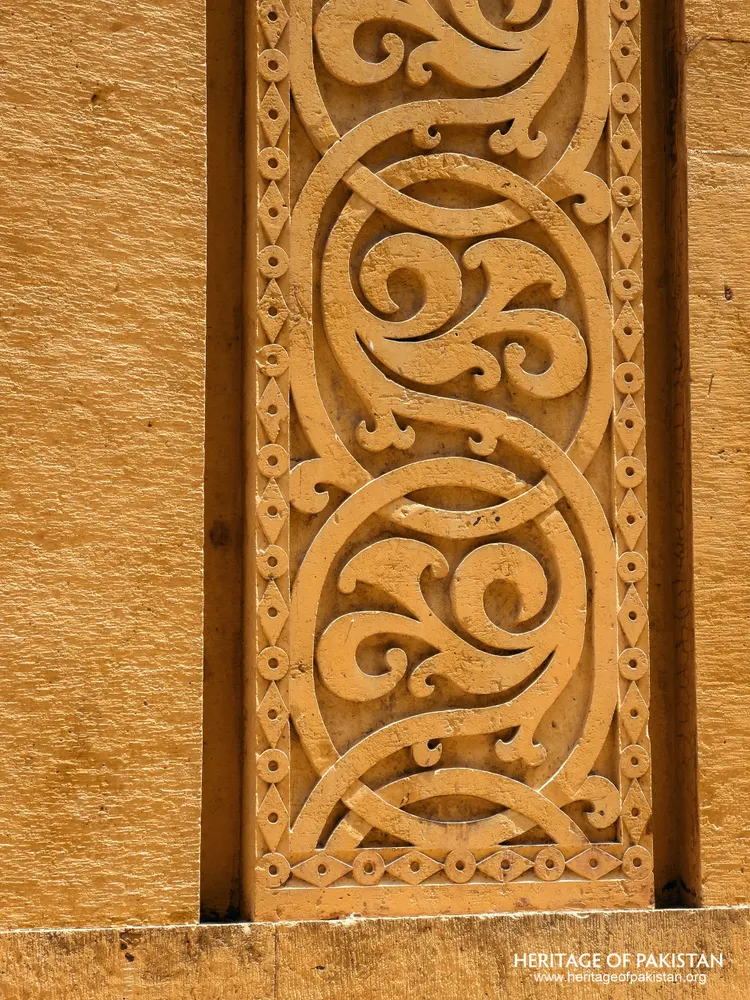 Carved yellow stone panel with interlocking scroll ornament