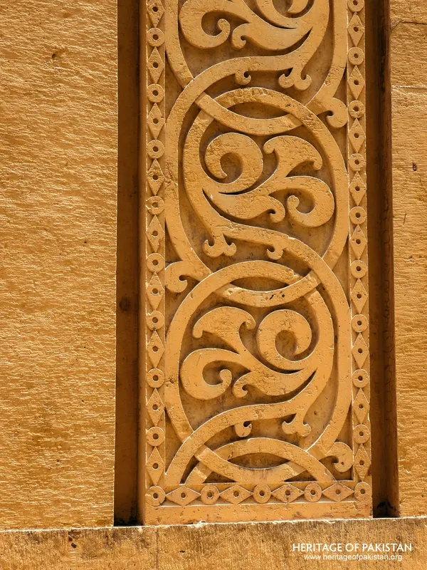 Carved yellow stone panel with interlocking scroll ornament