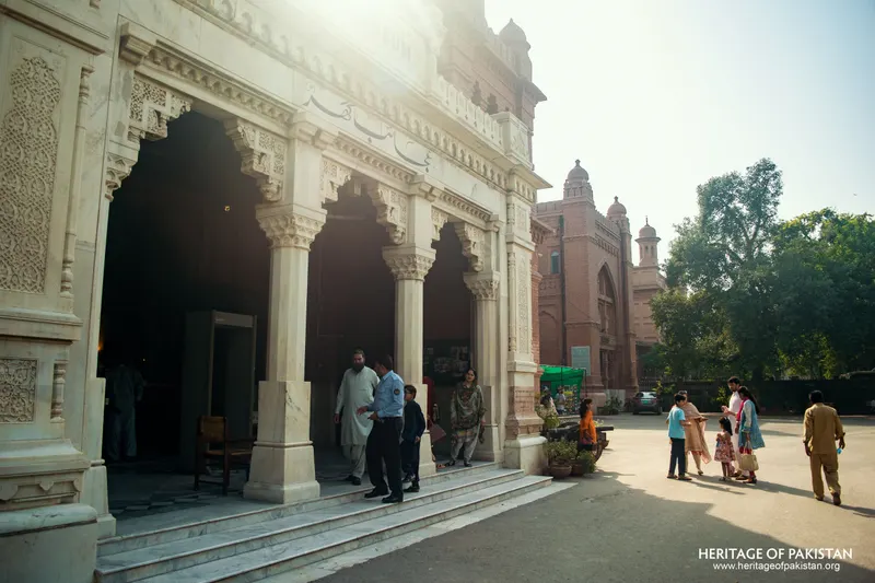 White marble portico beside a red-brick building with visitors outside