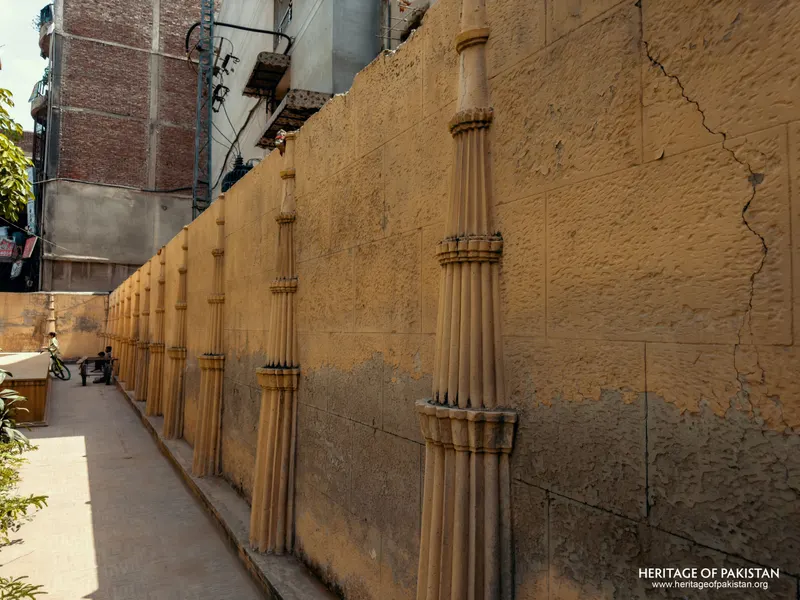 Fluted column shafts along a cracked rendered boundary wall