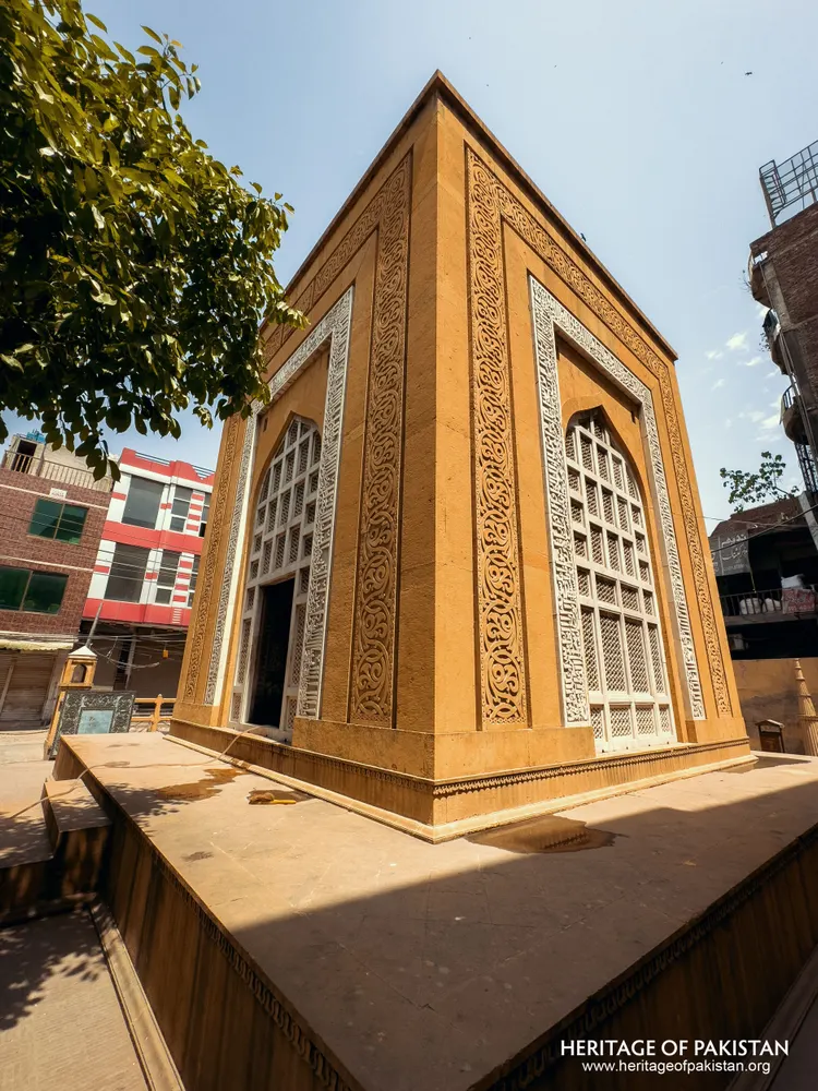 Yellow stone structure with white marble jali screens and carved decorative borders