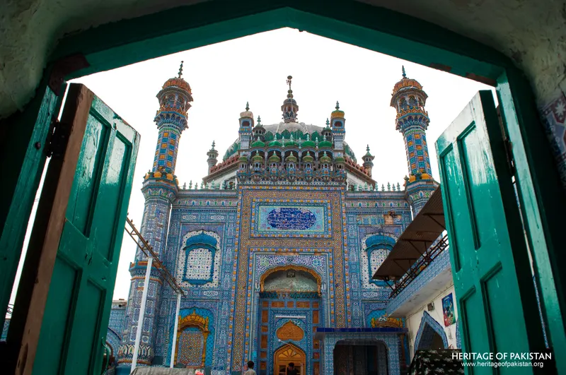Tiled shrine front viewed through an arched green-doored gateway