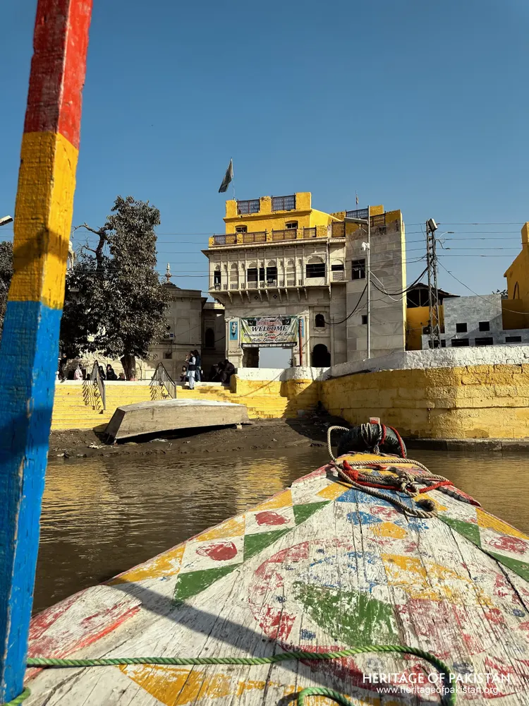 View from the boat toward Sadhu Belo Temple's riverside ghat and yellow-topped tower
