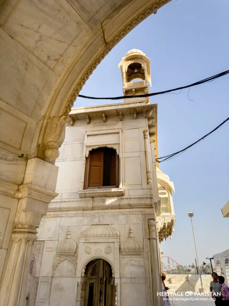 Small domed bell tower on Sadhu Belo Temple's marble upper storey, seen through an arch