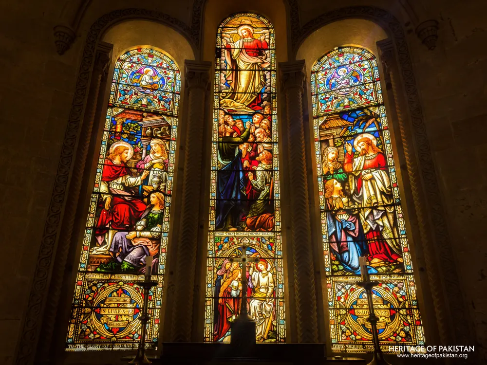 Close view of the triptych stained-glass window's narrative panels at Holy Trinity Church