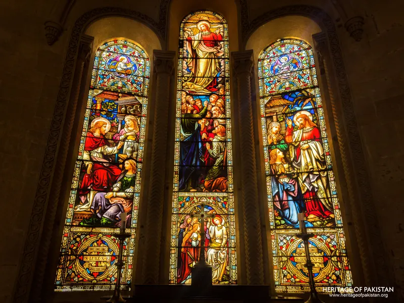 Close view of the triptych stained-glass window's narrative panels at Holy Trinity Church