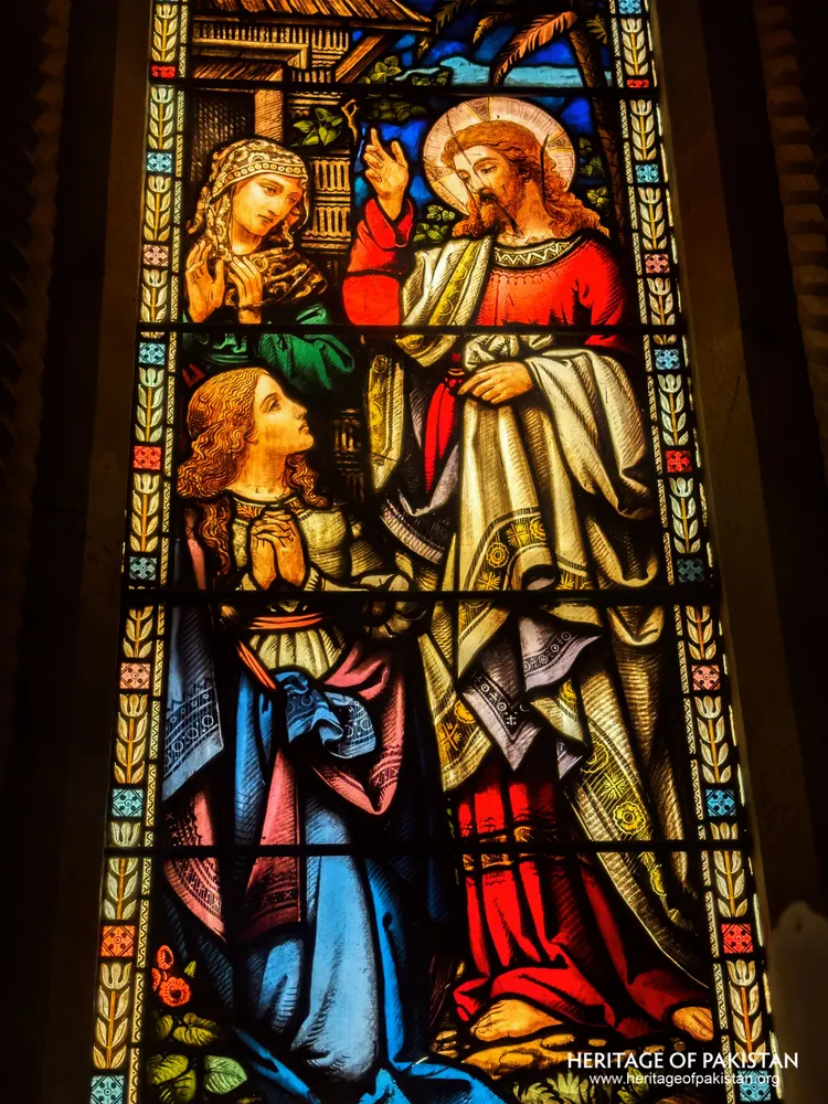 Stained-glass panel showing a healing scene beside a garden setting at Holy Trinity Church
