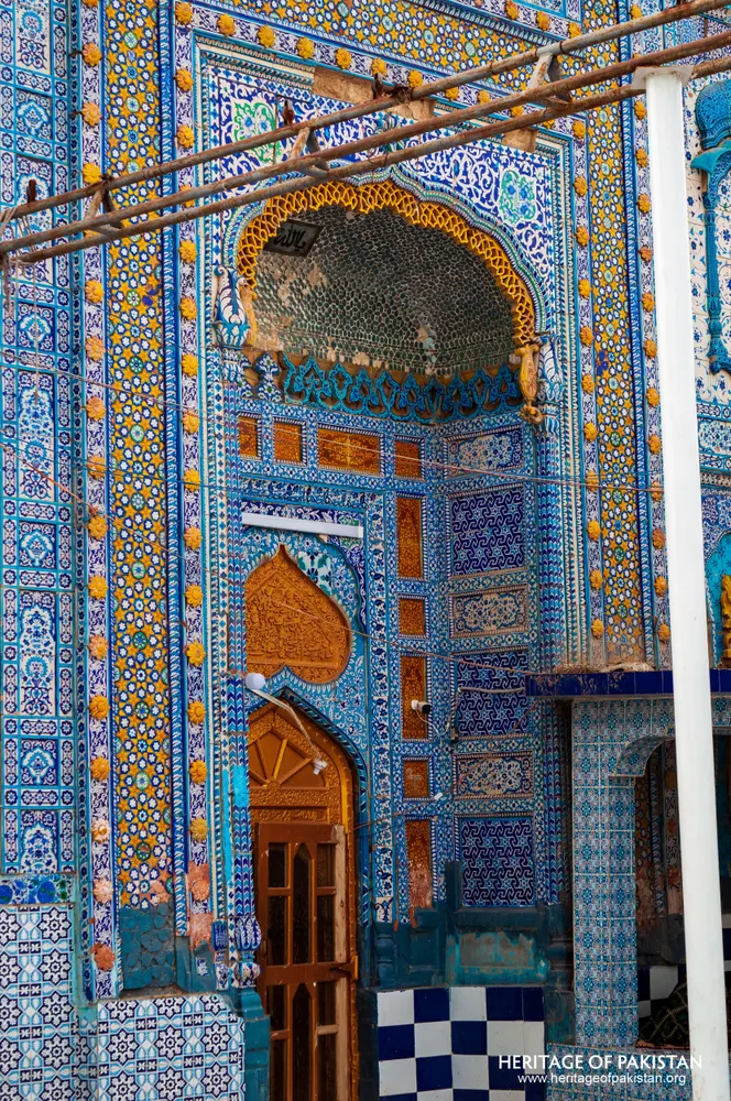 Tiled iwan with a wooden door and a honeycombed half-dome at the shrine