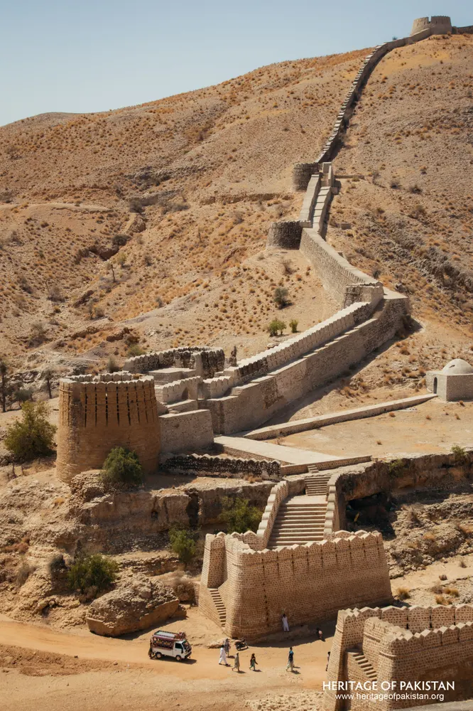 Stone fortification wall with bastions descending to a gateway