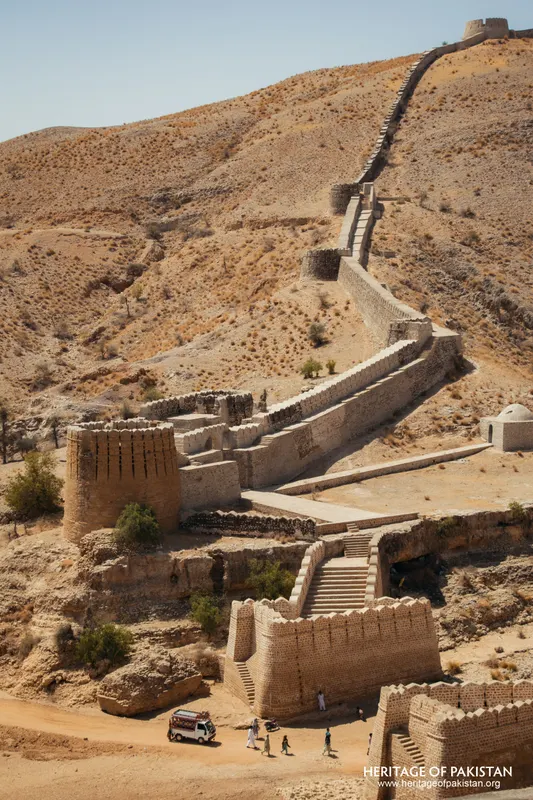 Stone fortification wall with bastions descending to a gateway