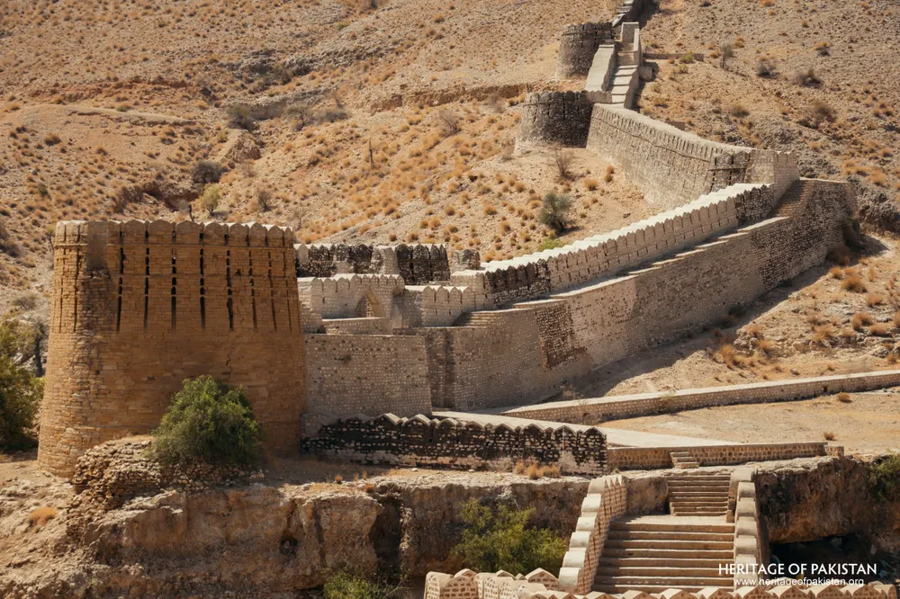 Square brick tower and crenellated wall climbing a dry hillside