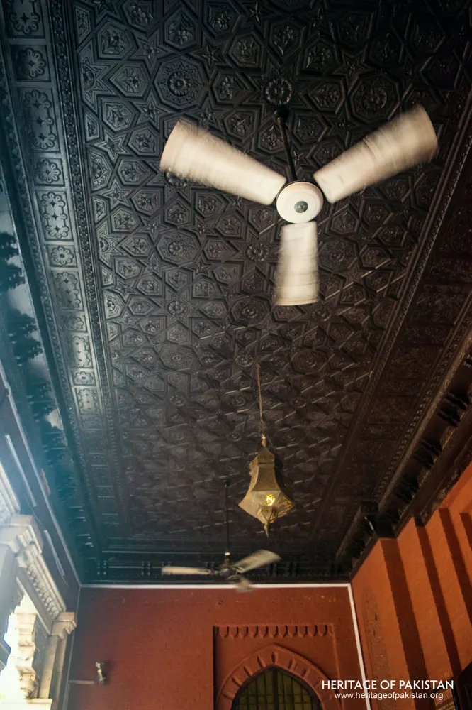 Dark patterned ceiling with a ceiling fan and hanging brass lantern