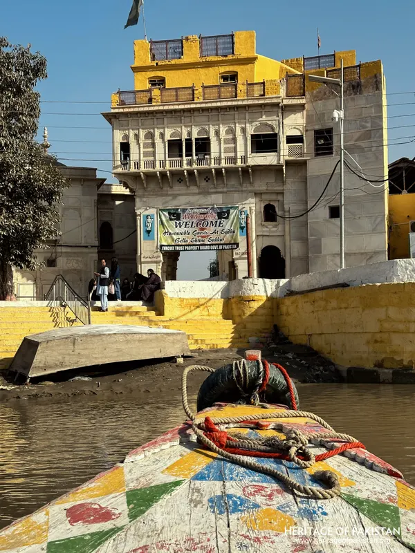 Boat arriving at the ghat of Sadhu Belo Temple with the yellow-topped tower behind