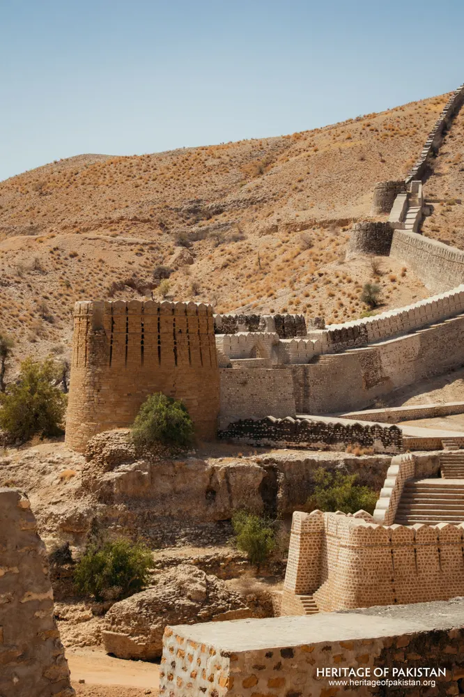 Brick tower beside a wall ascending a dry hillside