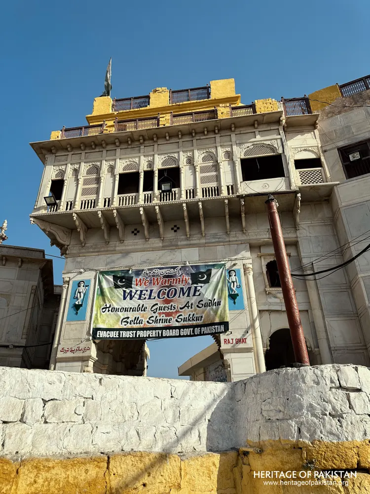 Low-angle view of Sadhu Belo Temple's carved marble tower with a welcome banner