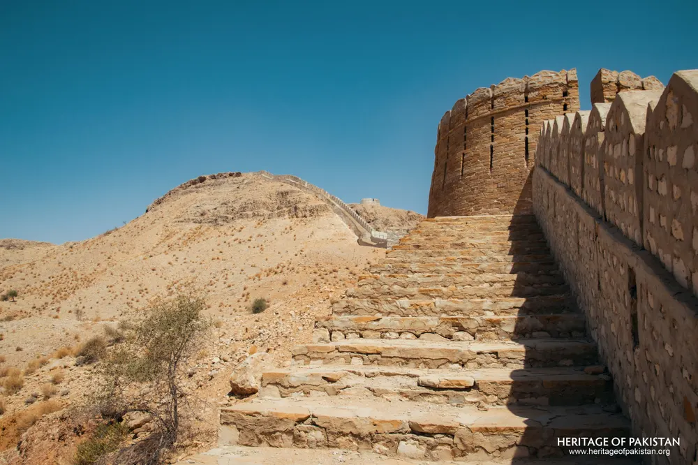 Stone staircase rising along a crenellated wall toward a round bastion