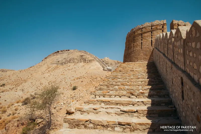 Stone staircase rising along a crenellated wall toward a round bastion