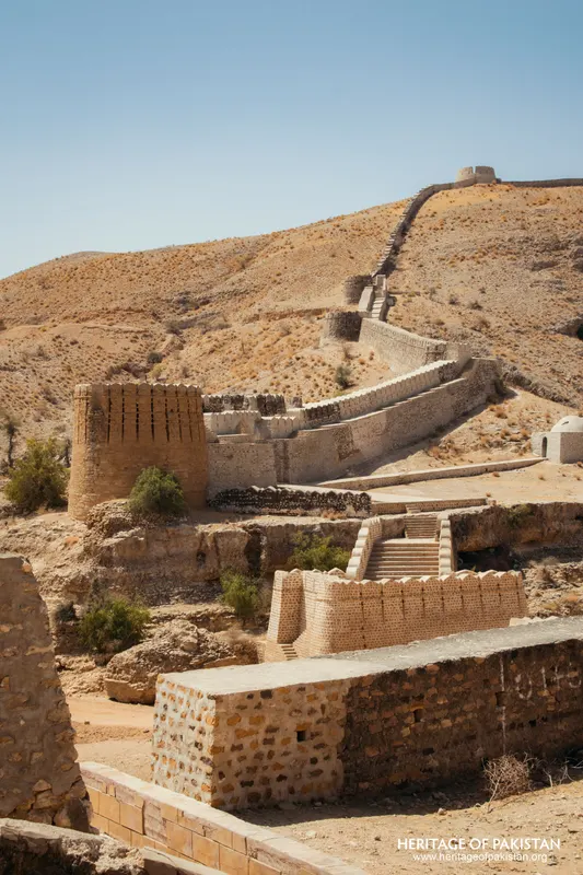 Stepped stone wall and brick tower on a bare hillside