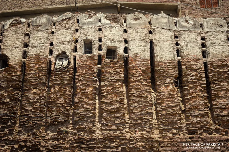 Close-up of Pakka Qila's rampart with small arched window recesses along its buttress ribs