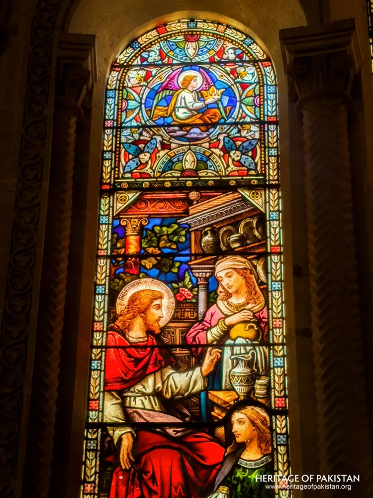 Full stained-glass panel of Christ with Mary and Martha beneath a winged angel roundel at Holy Trinity Church