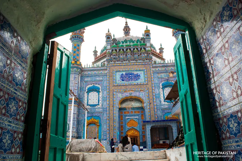 Shrine facade framed by a tiled gateway with devotees at the entrance